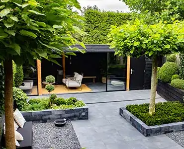 logo-Cour arrière aménagée en jardin urbain avec terrasse pavée, bacs de verdure et coin détente vitré